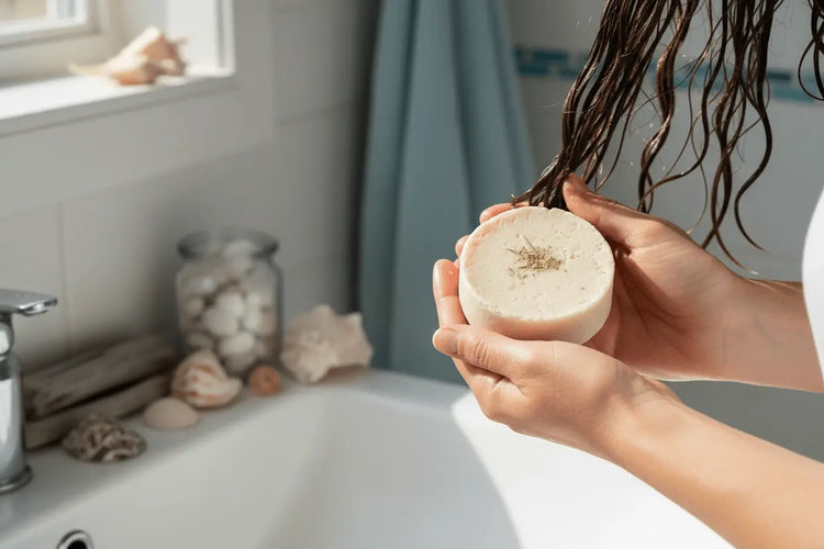 Beach Rain - Coastal Bathroom Hands holding beach rain shampoo bar in coastal bathroom with blue and white decor and seashells