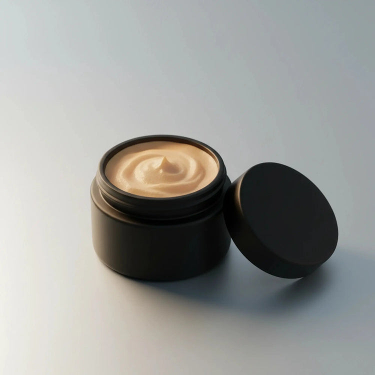 An open black cosmetic jar filled with a beige cream or balm, with its black lid resting beside it on a clean light gray background.