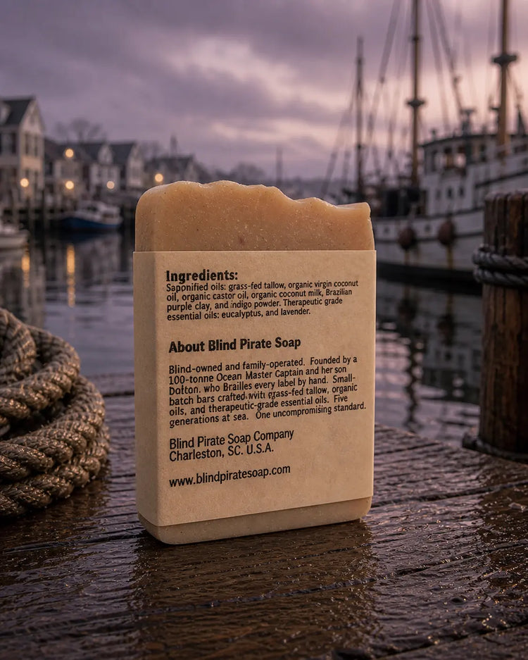 Windward tallow soap back panel, ingredients and brand story, wet harbor dock and tall fishing ships behind. Blind Pirate Soap Co.