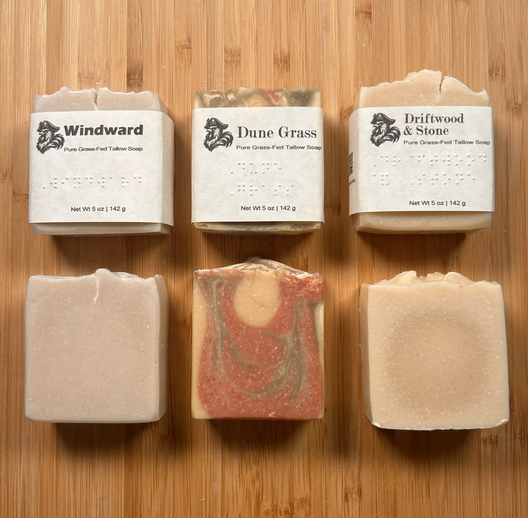Beach & Dunes set — three wrapped bars above three naked bars showing swirled tallow textures on warm bamboo surface
