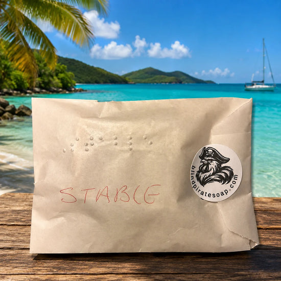 Stowaway Discovery Set | Single Braille-labeled glassine-wrapped Stowaway soap sample sealed with Blind Pirate Soap Co. logo sticker