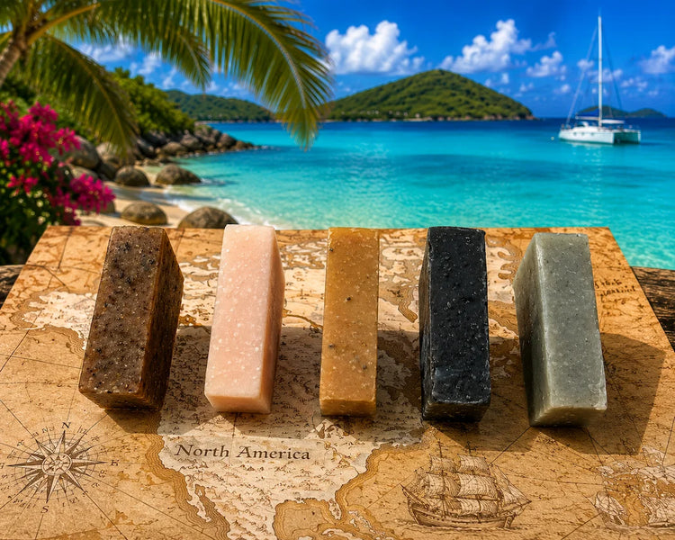 Five Stowaway soap sample bars standing upright on sandy tropical beach, Blind Pirate Soap Co. Braille labels visible
