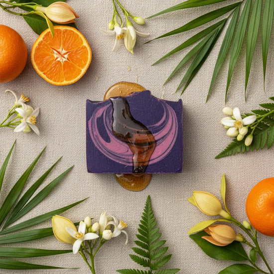 Overhead view of Alani Moani purple soap with tangerine, orange blossoms, ylang ylang flowers, and raw honey on natural linen
