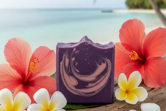Alani Moani handcrafted purple soap bar with alkanet root and pink rose clay, surrounded by tropical Hawaiian plumeria and hibiscus flowers