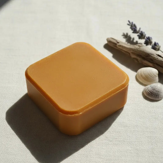 Sovereign Gold square amber artisan soap bar with rounded corners on linen, styled with dried lavender, driftwood, and seashells — Blind Pirate Soap Company.