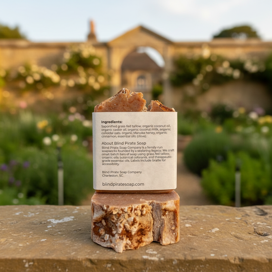Back panel of Oatmeal & Honey tallow soap bar in warm golden light, the grand stone country manor house softly blurred behind.