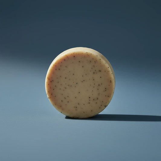 Beach Rain | Grass Fed Tallow | Shampoo Bar Blind Pirate Soap Co. a gorgeous, round and tan shampoo puc stands on it's side.