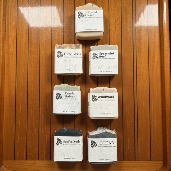 Seven Blind Pirate Soap Co. coastal bars in overhead flat lay on varnished teak yacht salon table.