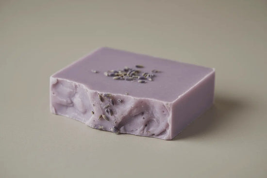 Purple soap bar with visible herbs on a beige background