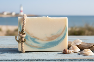 Bar of soap with a rope and anchor decoration on a wooden surface with seashells and a beach background.