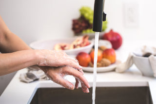 Hands washing with luxurious organic tallow soap lather at clean kitchen sink with fresh produce nearby