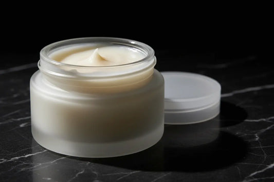 Ditch Kit clear lip balm by Blind Pirate Soap Co in a frosted glass jar with lid off showing ivory white lip balm, photographed on dark marble with dramatic lighting.
