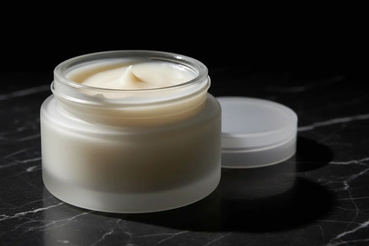Ditch Kit clear lip balm by Blind Pirate Soap Co in a frosted glass jar with lid off showing ivory white lip balm, photographed on dark marble with dramatic lighting.