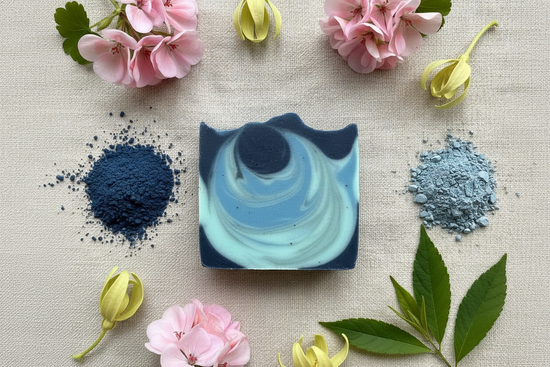Overhead view of soft blue swirled Ocean soap with spirulina powder, blue clay, geranium, ylang ylang, and patchouli on linen