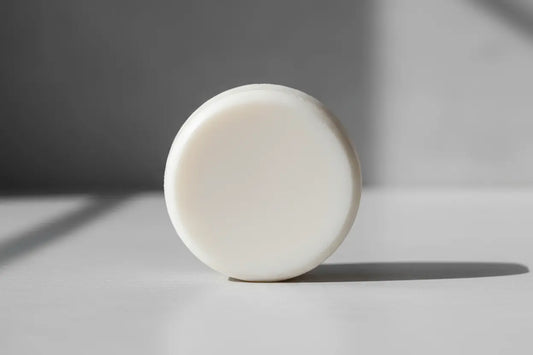 plain white round shampoo tallow bar  unscented no added ingredients  only 3 ingredients a beautiful white round shampoo bar stands on it's side in the light of a gentle sun.  