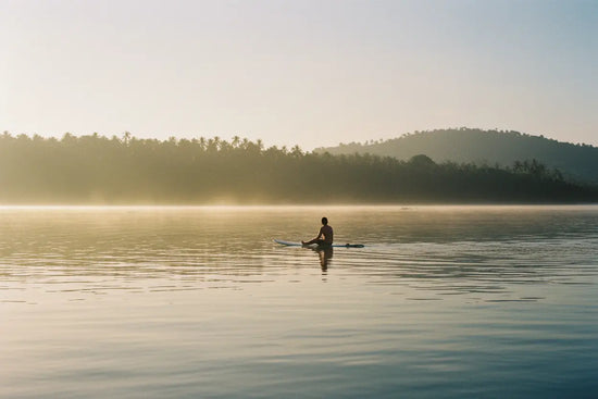 Surfer Suds | A surfer sitting on their board in still water, waiting for sets at Siargao — patience before the perfect wave.