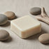 Still Water square ivory tallow shampoo passage bar on natural linen with smooth river stones and driftwood — Blind Pirate Soap.