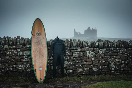 Surfer Suds | A surfboard resting against a mossy stone wall in the cold misty dawn at Thurso East, Scotland