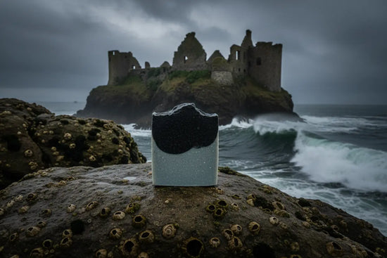Surfer Suds unwrapped tallow soap bar on coastal rock, a ancient castle on an island rising from the grey Thurso waters