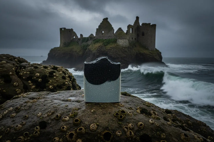 Surfer Suds unwrapped tallow soap bar on coastal rock, a ancient castle on an island rising from the grey Thurso waters