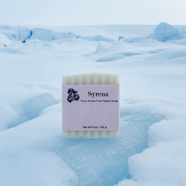 Syrena Pure Grass-Fed Tallow Soap front panel on arctic snow — pirate logo, Braille label, Net Wt 5 oz.