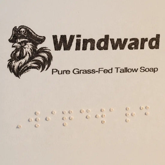 Windward label close-up — pirate logo, title, and full Braille block on pale kraft paper. Blind Pirate Soap Co.
