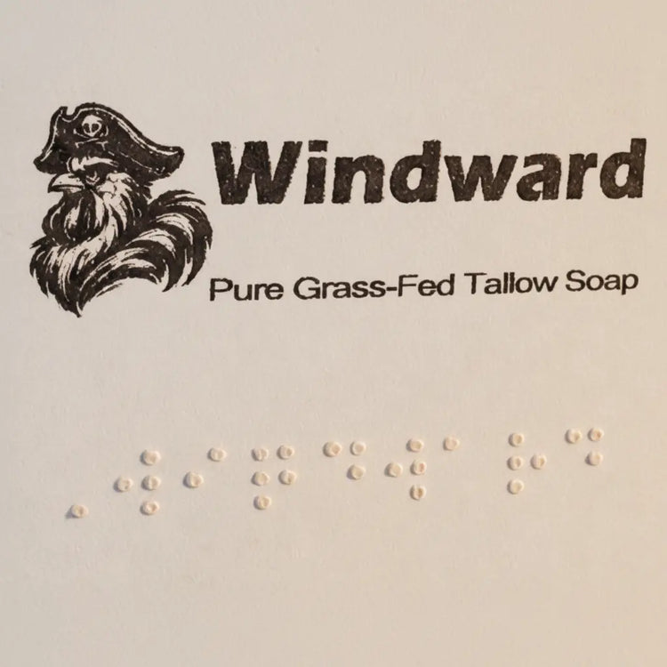 Windward label close-up — pirate logo, title, and full Braille block on pale kraft paper. Blind Pirate Soap Co.
